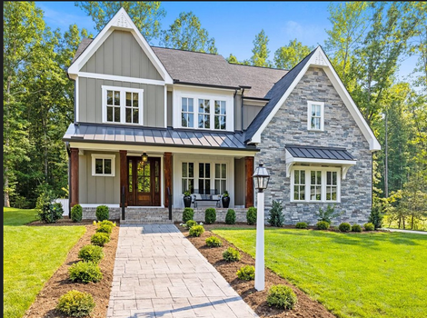 A two-story suburban home with stone and wood siding, a dark roof, and a paved walkway leading to the front entrance.