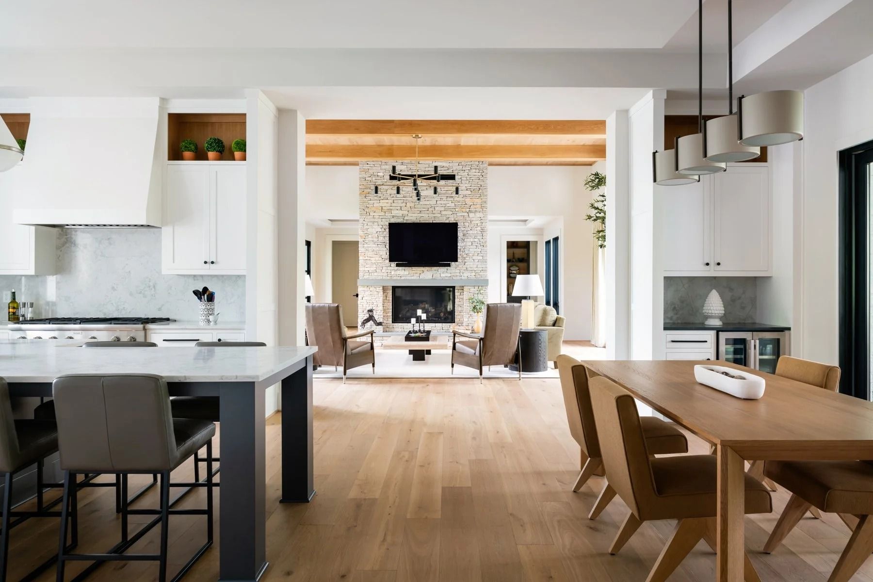 A bright, open-concept home interior featuring a kitchen with a white island and a dining area leading to a living room.