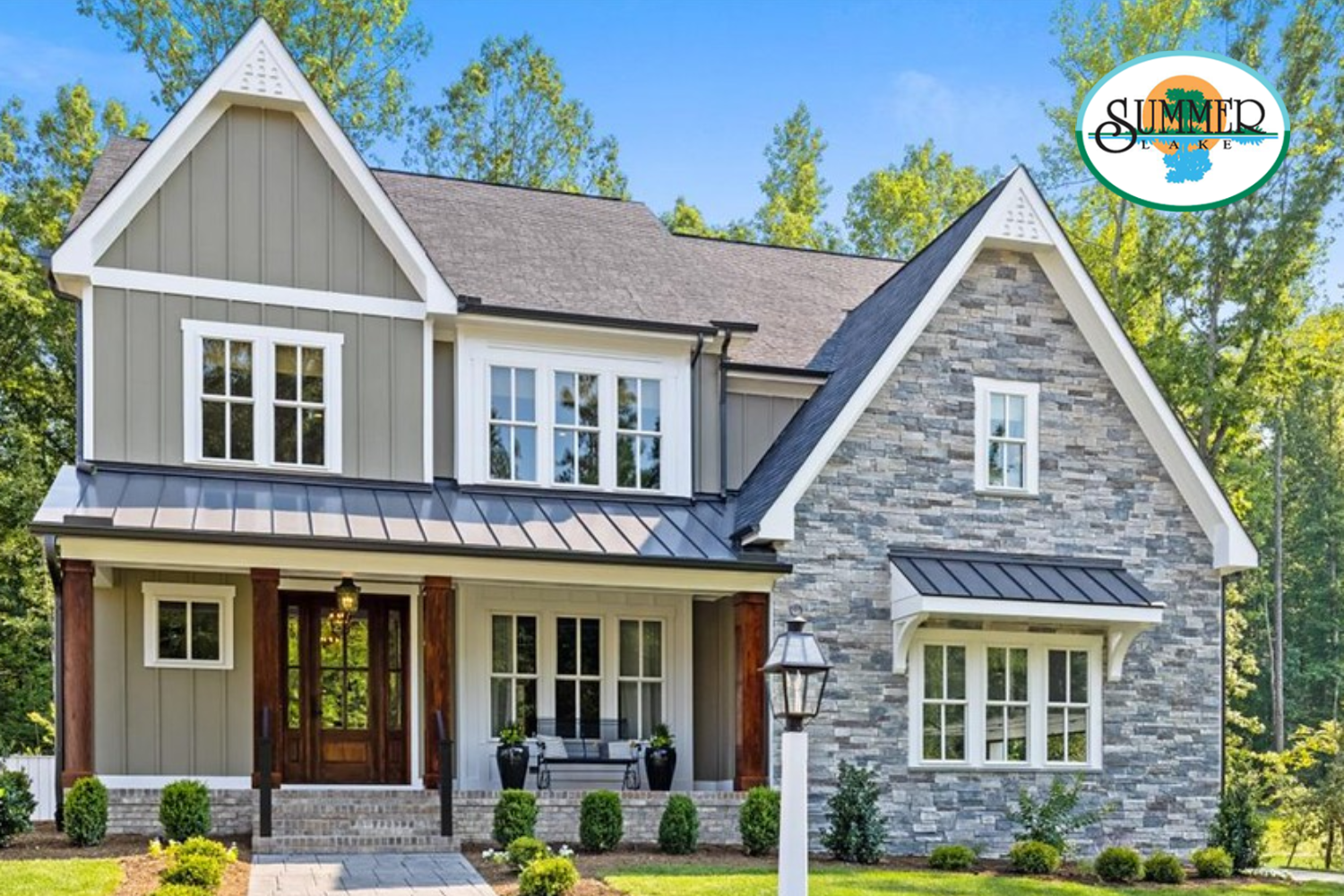 A two-story suburban home with green siding, a stone facade, a dark metal roof, and a front porch, set among trees.