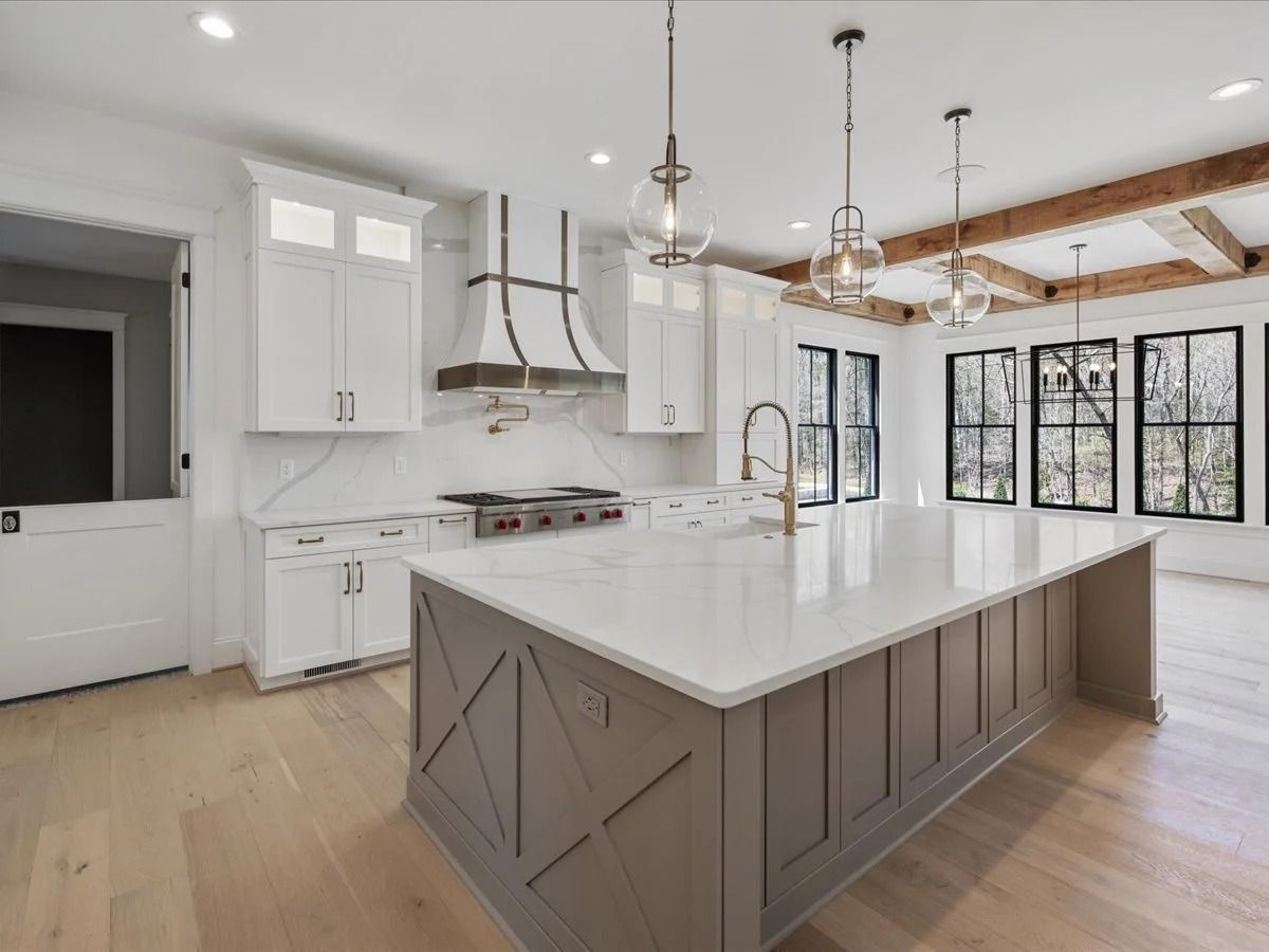 Bright modern kitchen with white cabinets, large island, wood floors, and black-framed windows