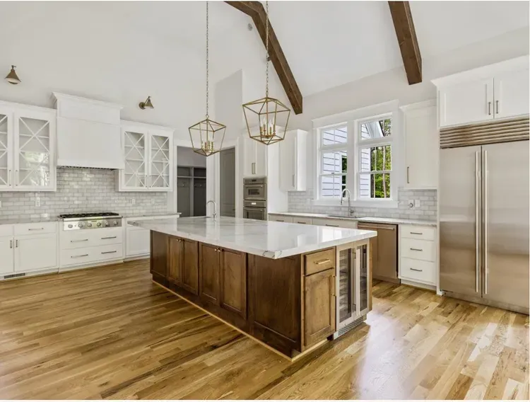 Bright modern kitchen with white cabinets, wood floors, central island, and stainless steel appliances