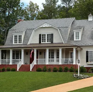 Large white house with gray roof, front porch, and manicured lawn