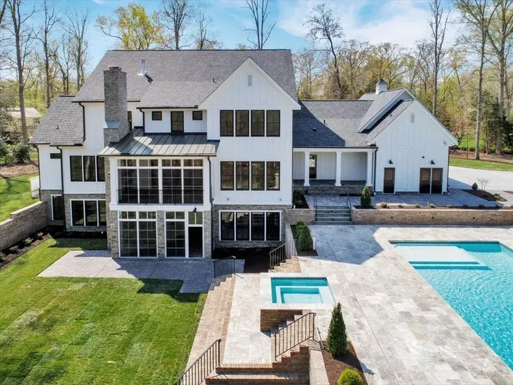Large modern house with a backyard pool, patio, and landscaped lawn