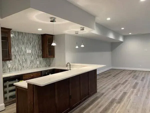 Modern open-concept kitchen with dark cabinets, white island, pendant lights, and gray flooring