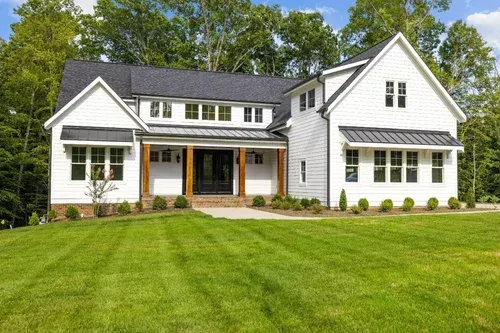 White two-story suburban house with a large green lawn and front porch