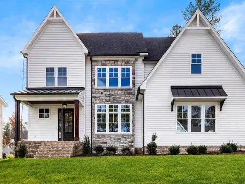 Suburban white two-story house with dark roof, blue-trimmed windows, and a green lawn