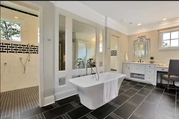 Modern bathroom with freestanding tub, glass shower, dark tile floor, and white vanity