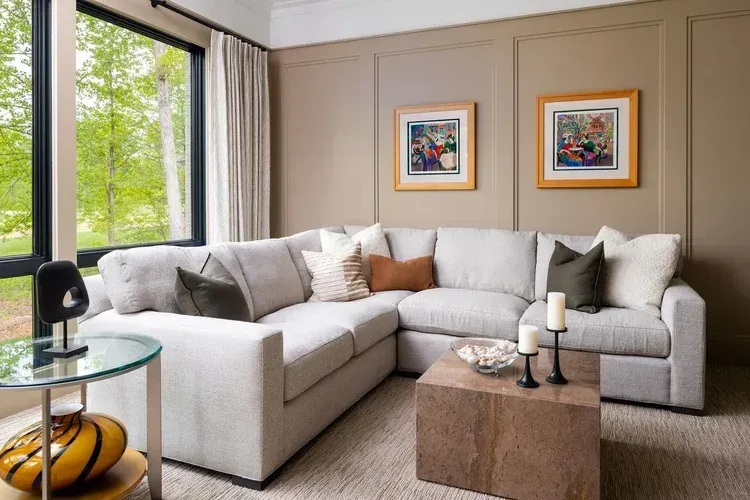 Bright living room with a light gray sectional, framed art, and a side table by a window