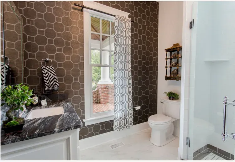 Elegant bathroom with brown hexagon wallpaper, white tub, window, and toilet.