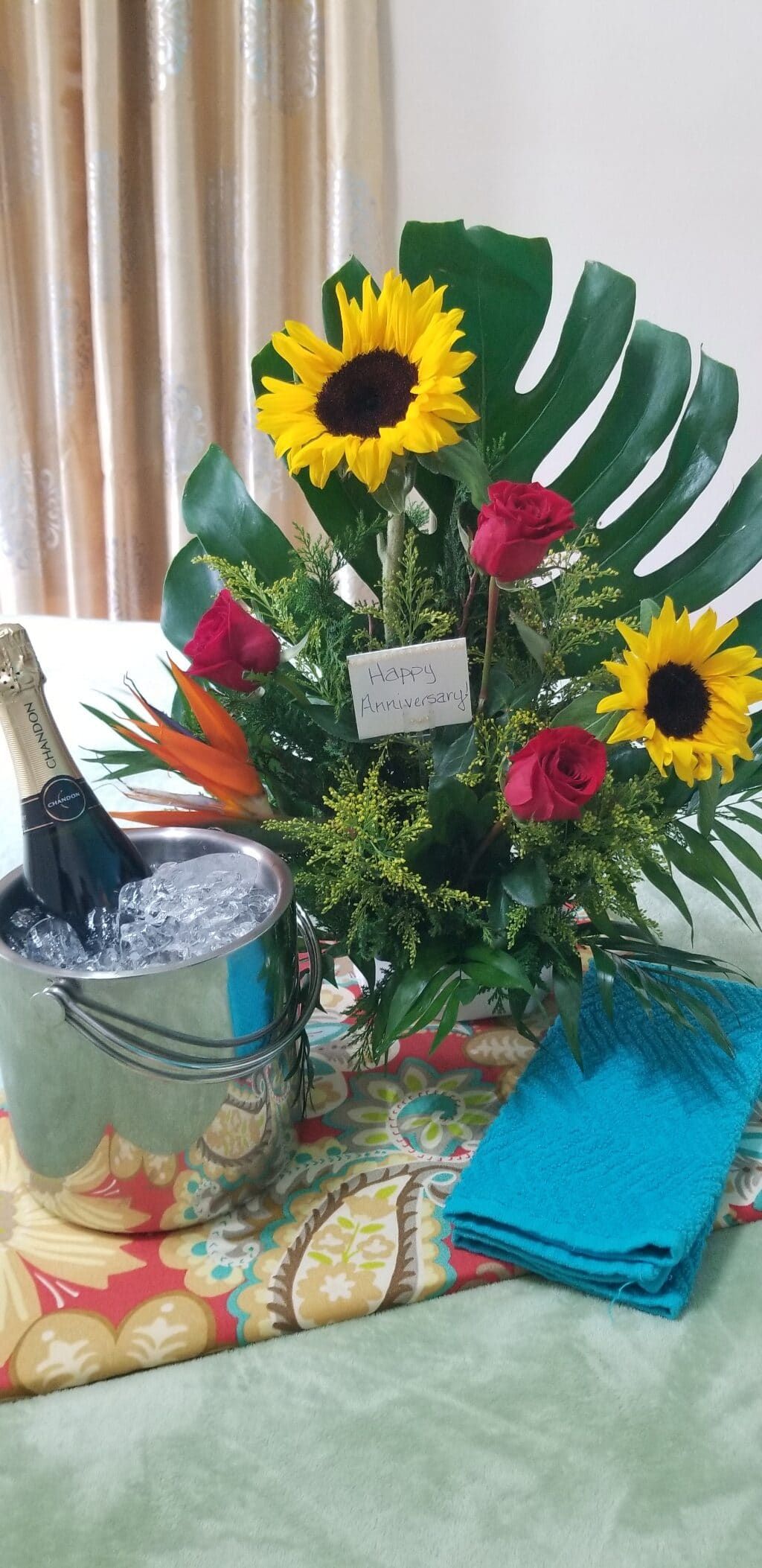 A table with a bouquet of flowers and a bucket of ice.