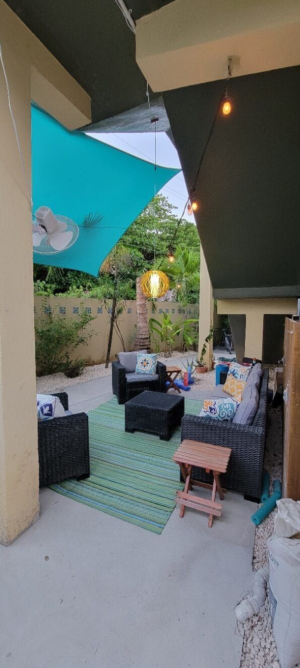 A patio with a lot of furniture and a blue umbrella.
