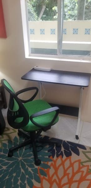 A green chair is sitting next to a black desk in a room.