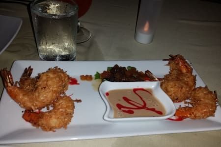 A plate of fried shrimp with sauce and a glass of water