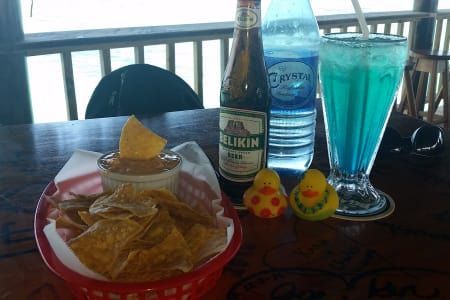A bottle of belkin beer sits on a table next to a basket of chips