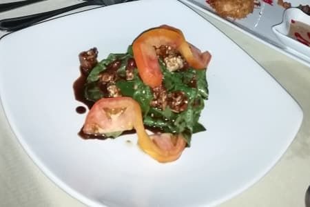 A salad with tomatoes and spinach on a white plate