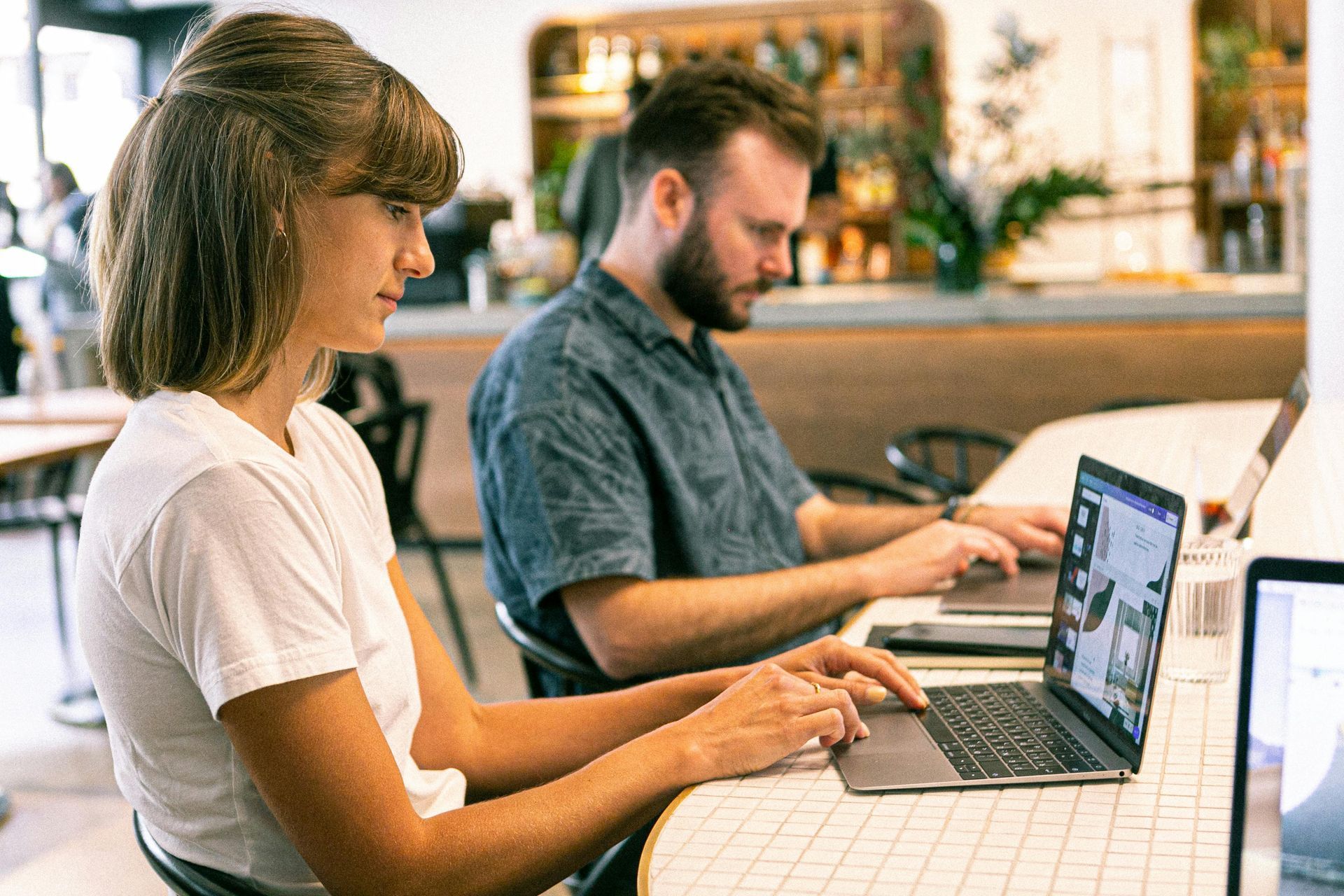 Two people working on laptops at a café table working on content for a Wilsona Marketing cleint