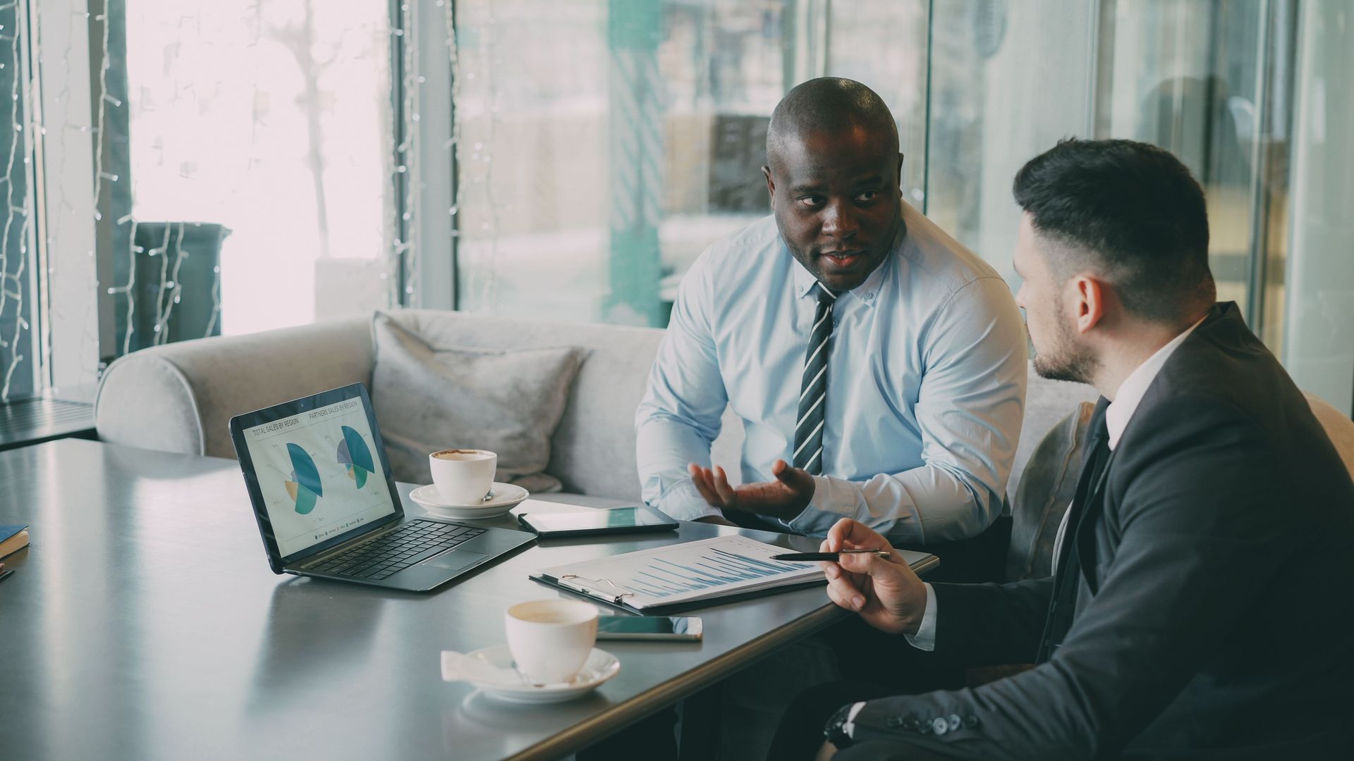 Two businesspeople reviewing charts on a laptop in a bright office meeting room at Wilsona Marketing
