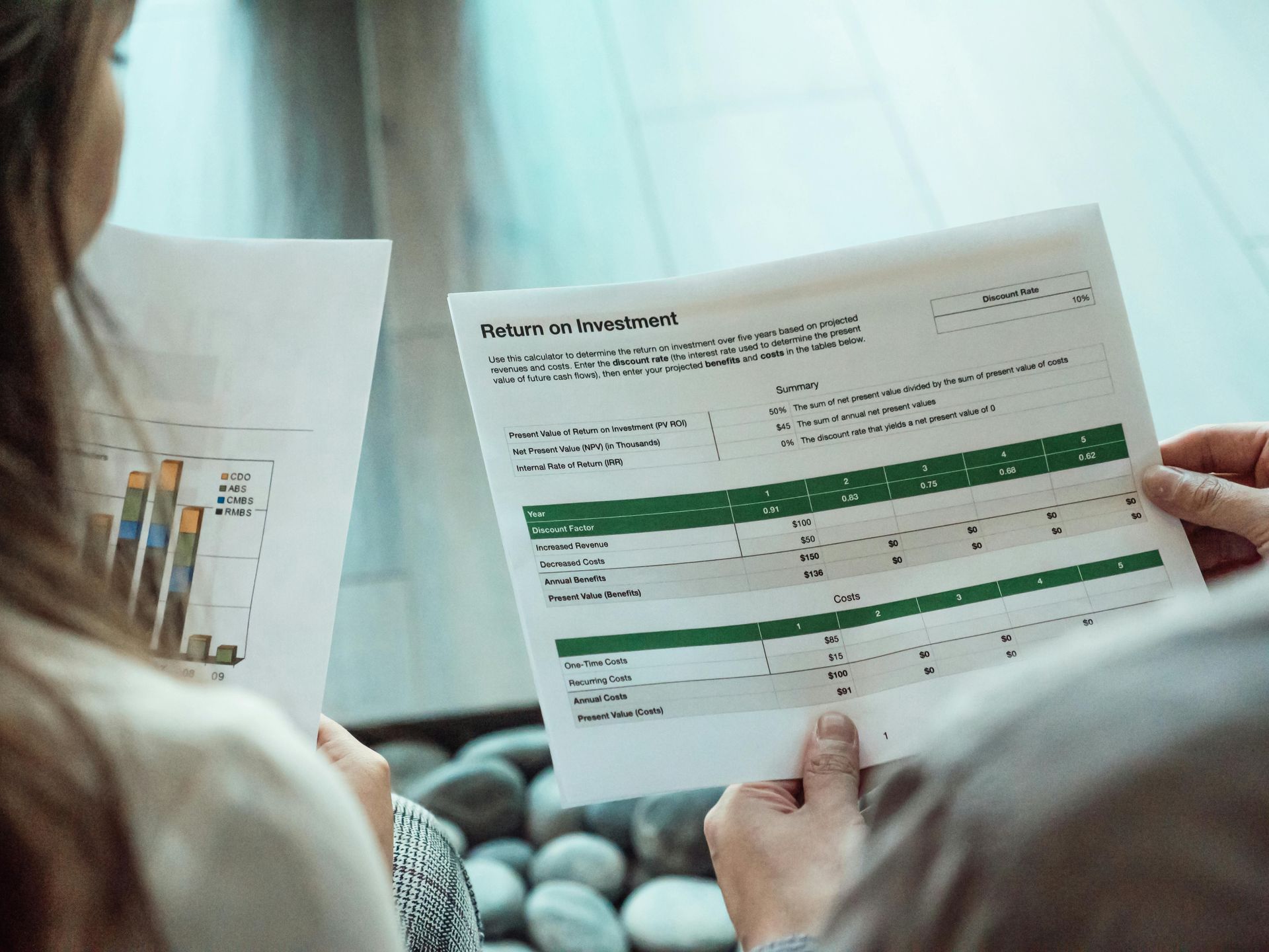 Person reviewing a printed report with green tables at a desk at Wilsona Marketing. Reviewing ROI marketing results