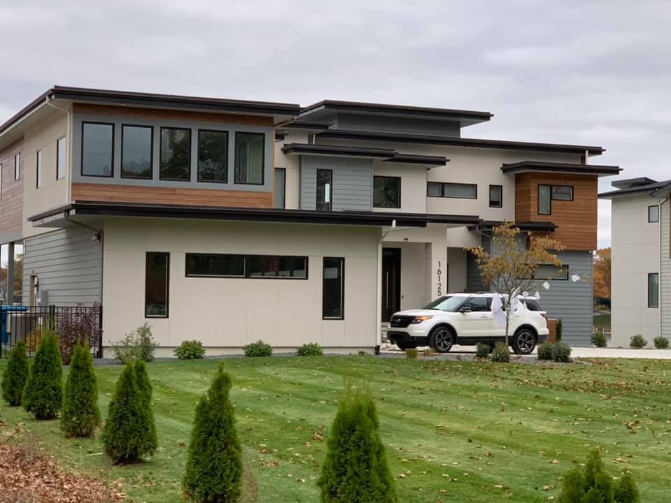 A white suv is parked in front of a large house.