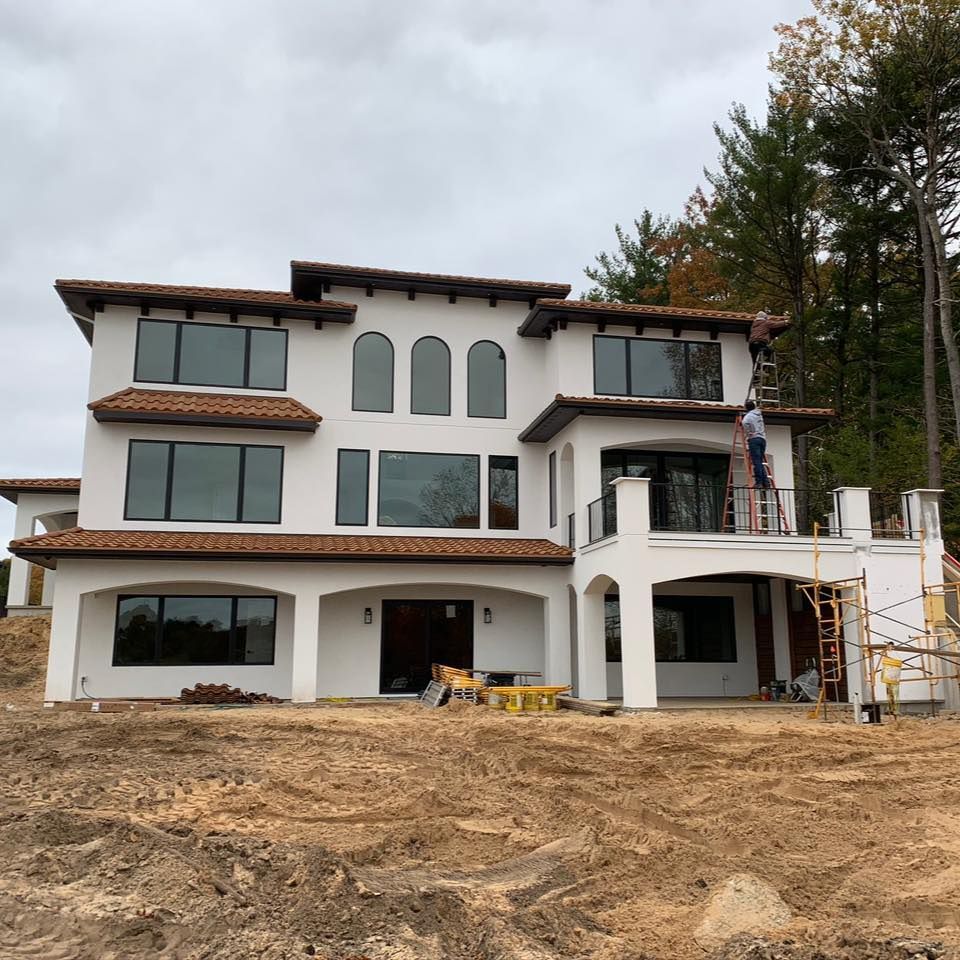 A brick house with a grill on the porch and a large window