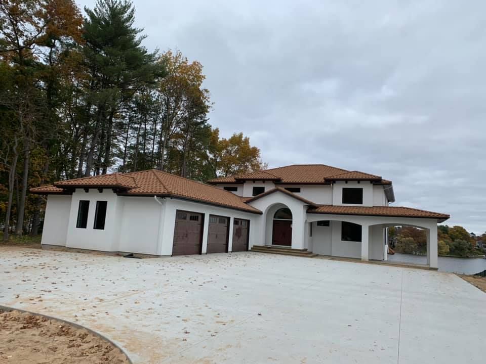 A large white house with a brown roof is surrounded by trees.