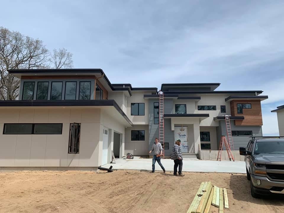 Two men are standing in front of a large house under construction.