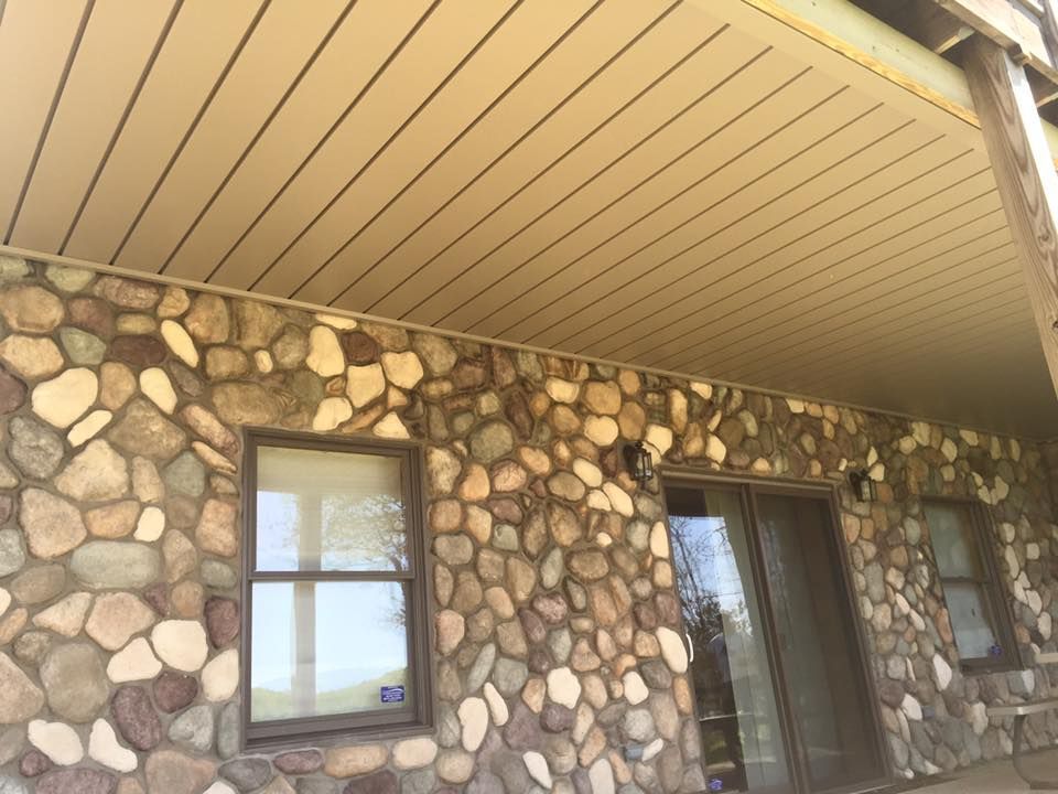 The front of a house with a stone wall and a porch.