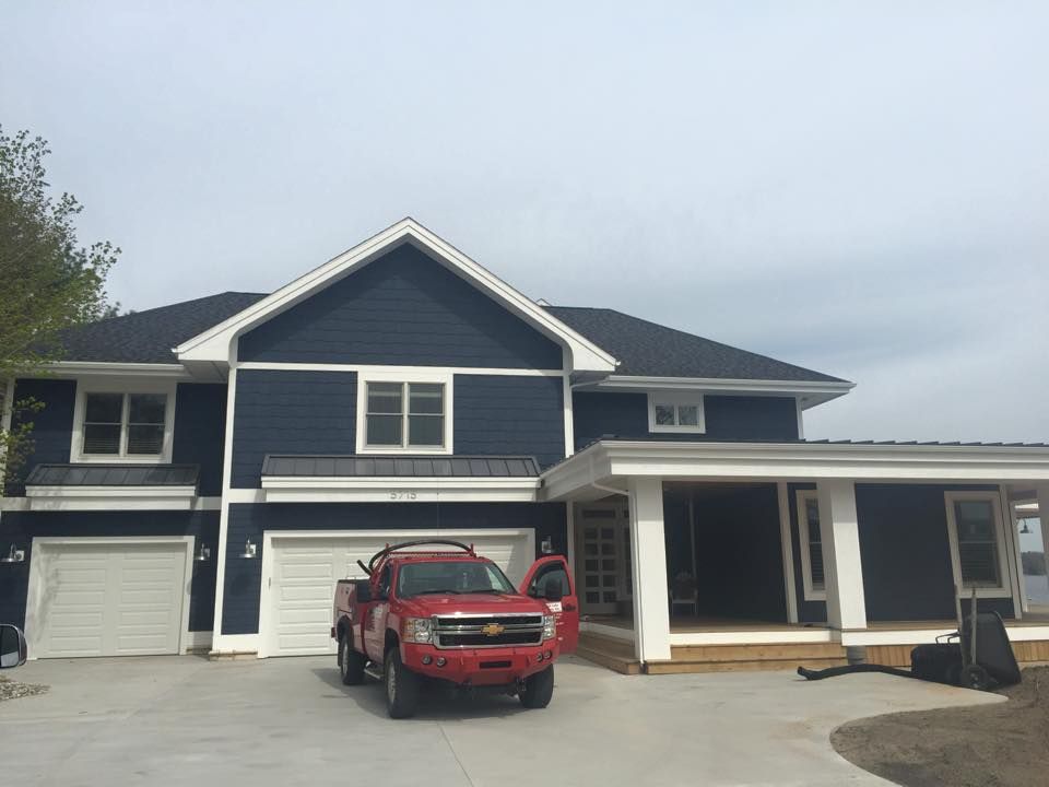 A red truck is parked in front of a large blue house