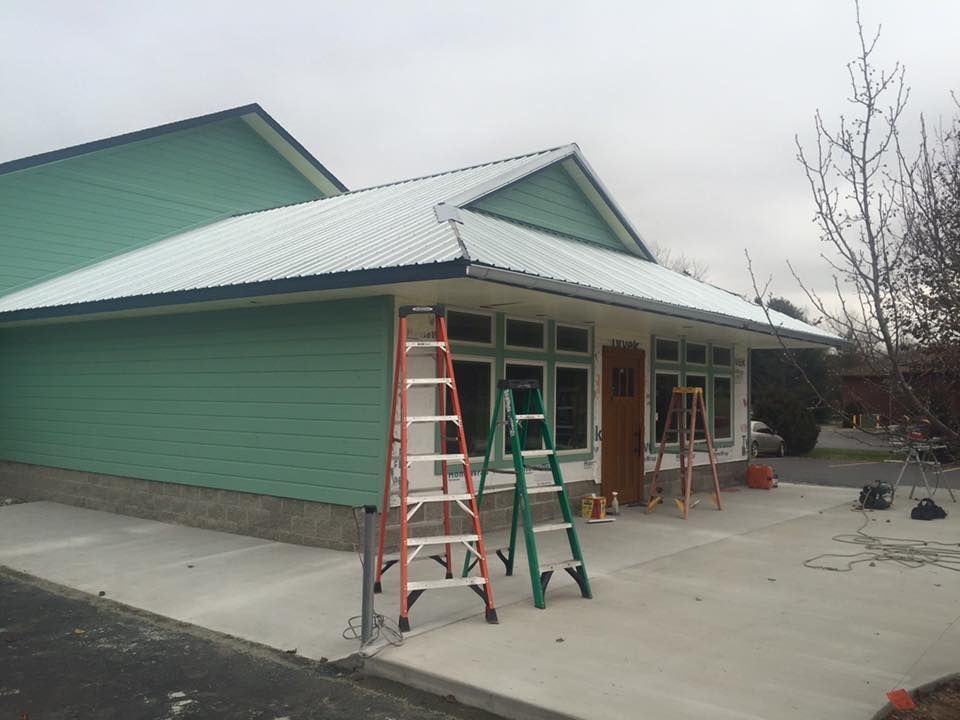 A green house with a white roof and two ladders in front of it