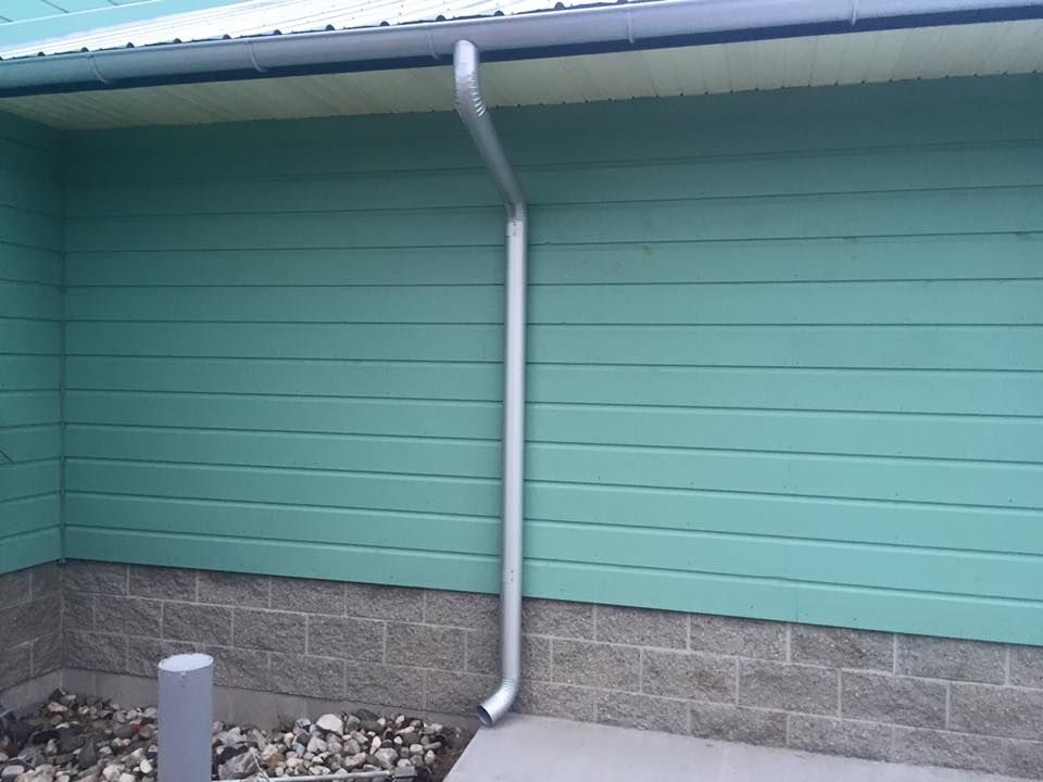 Building with copper gutters and brick facade, large windows, and an outdoor grill.