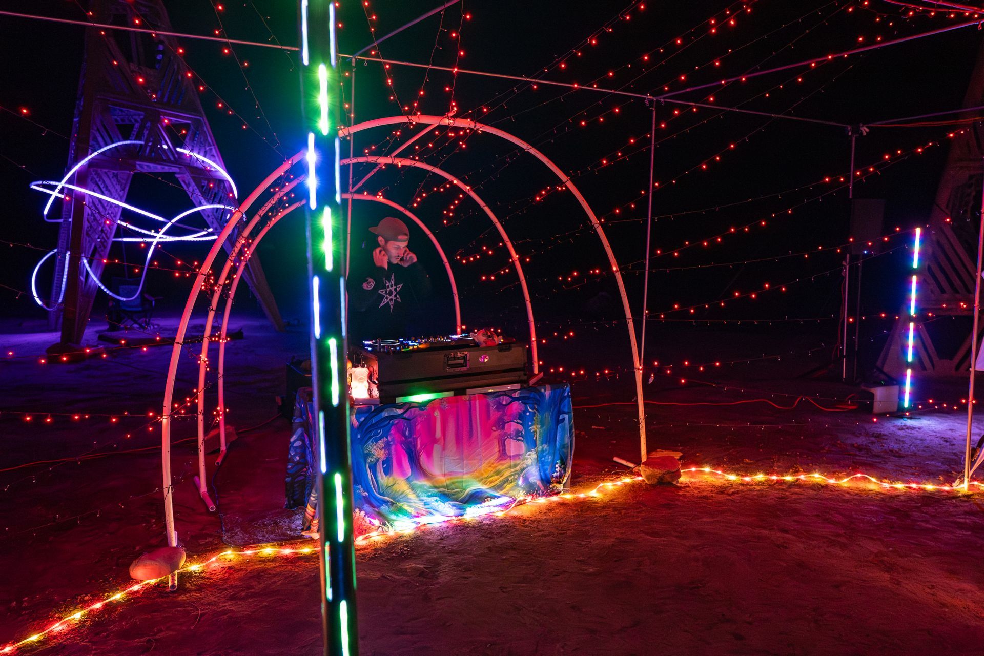 Nighttime illuminated DJ booth with colorful lights and archway.