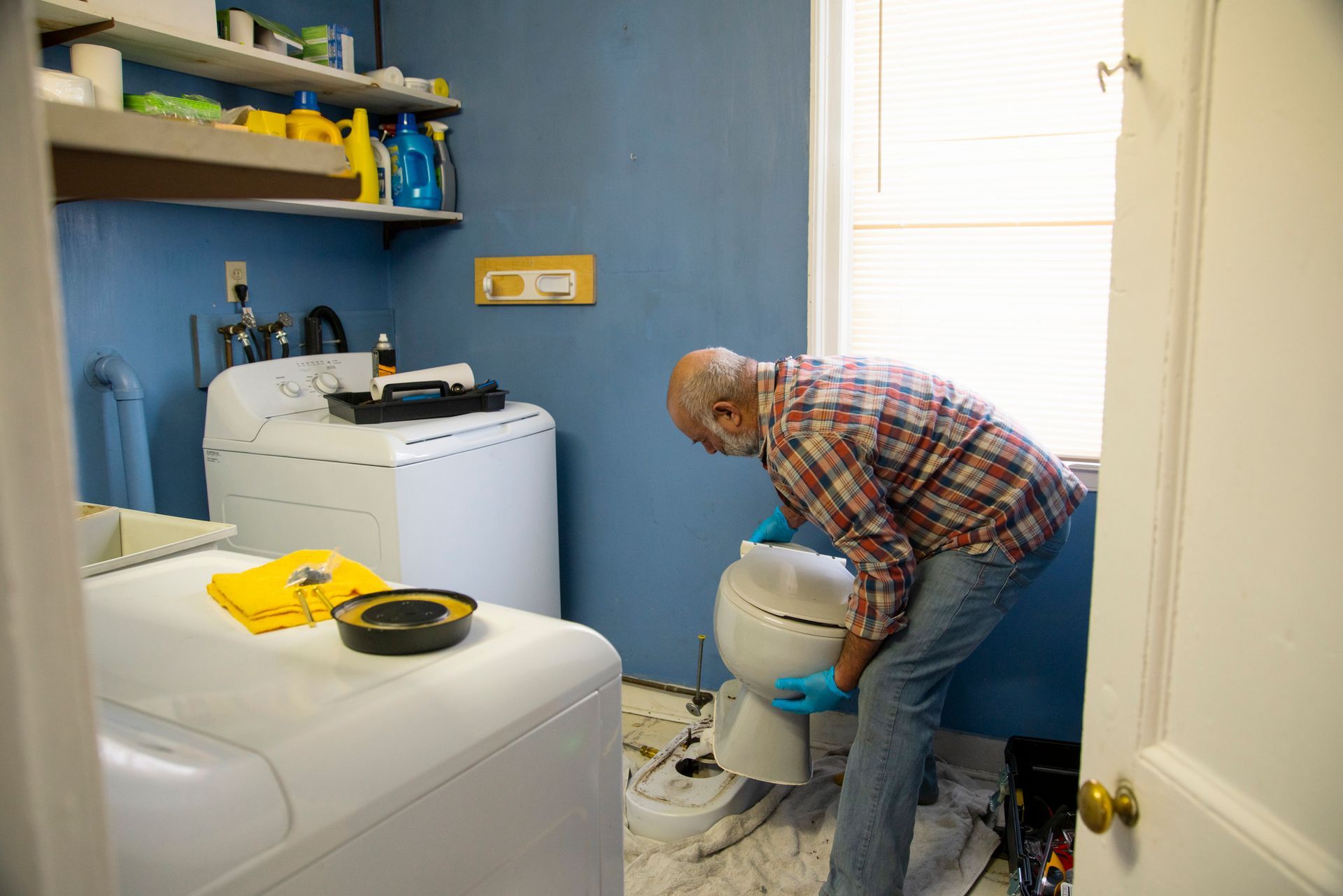 A tool bag filled with tools is under a sink in a kitchen.