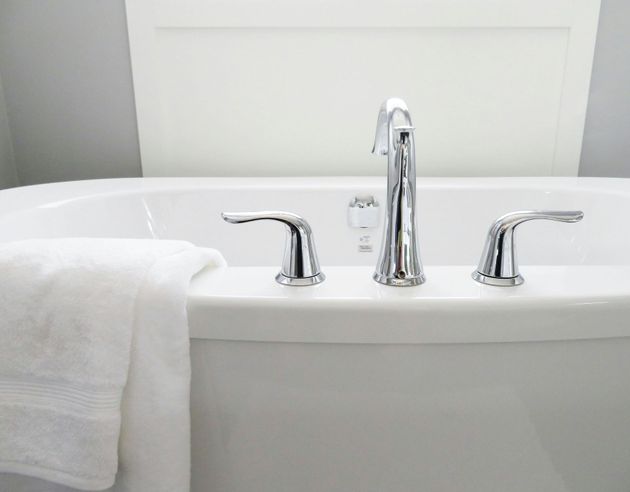 A close up of a bathtub with a shower head attached to it.