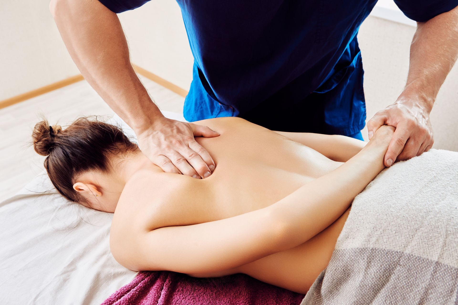 A woman is laying on a bed getting a massage from a man.