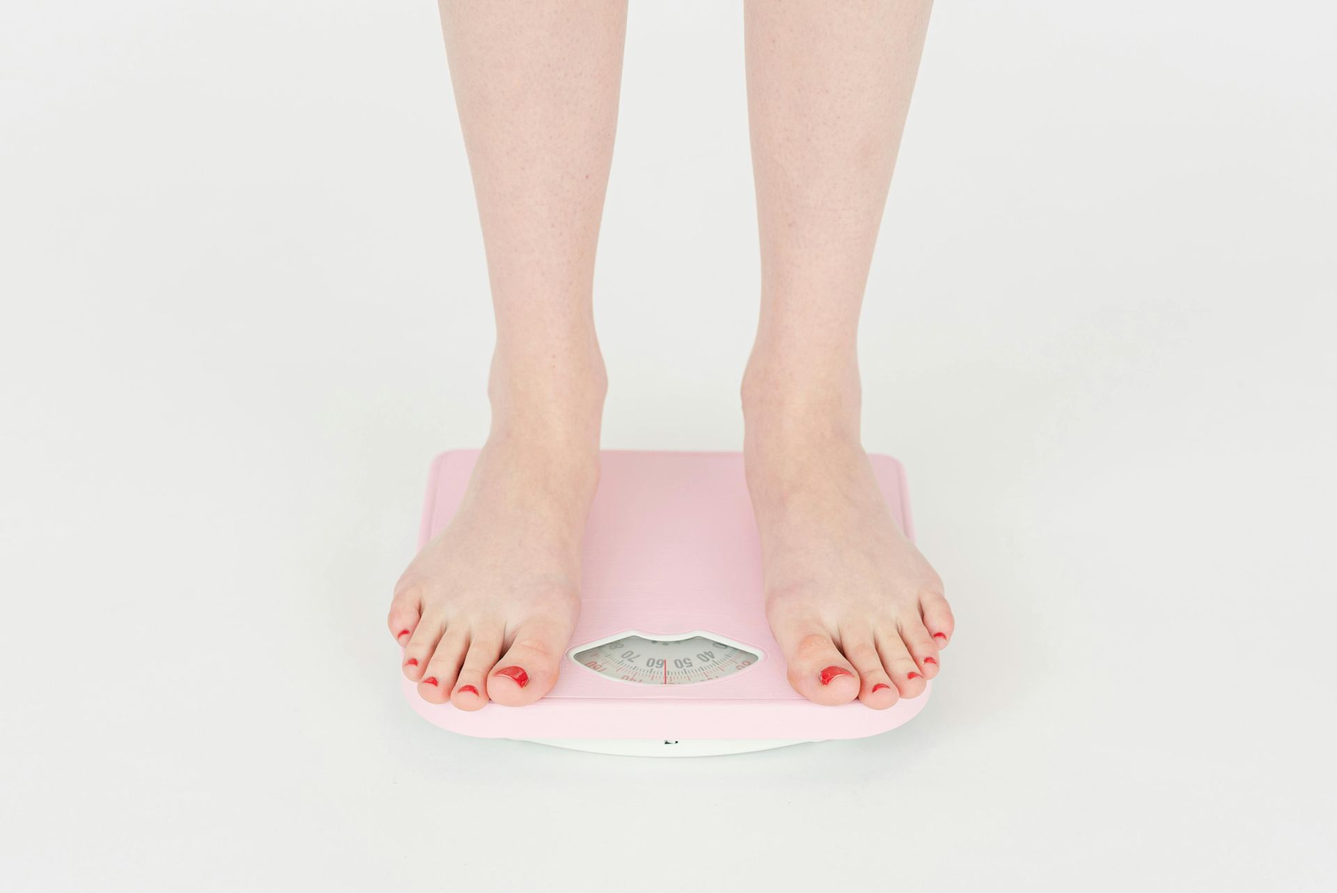 A woman is standing on a scale, weighing herself to optimize her health. 