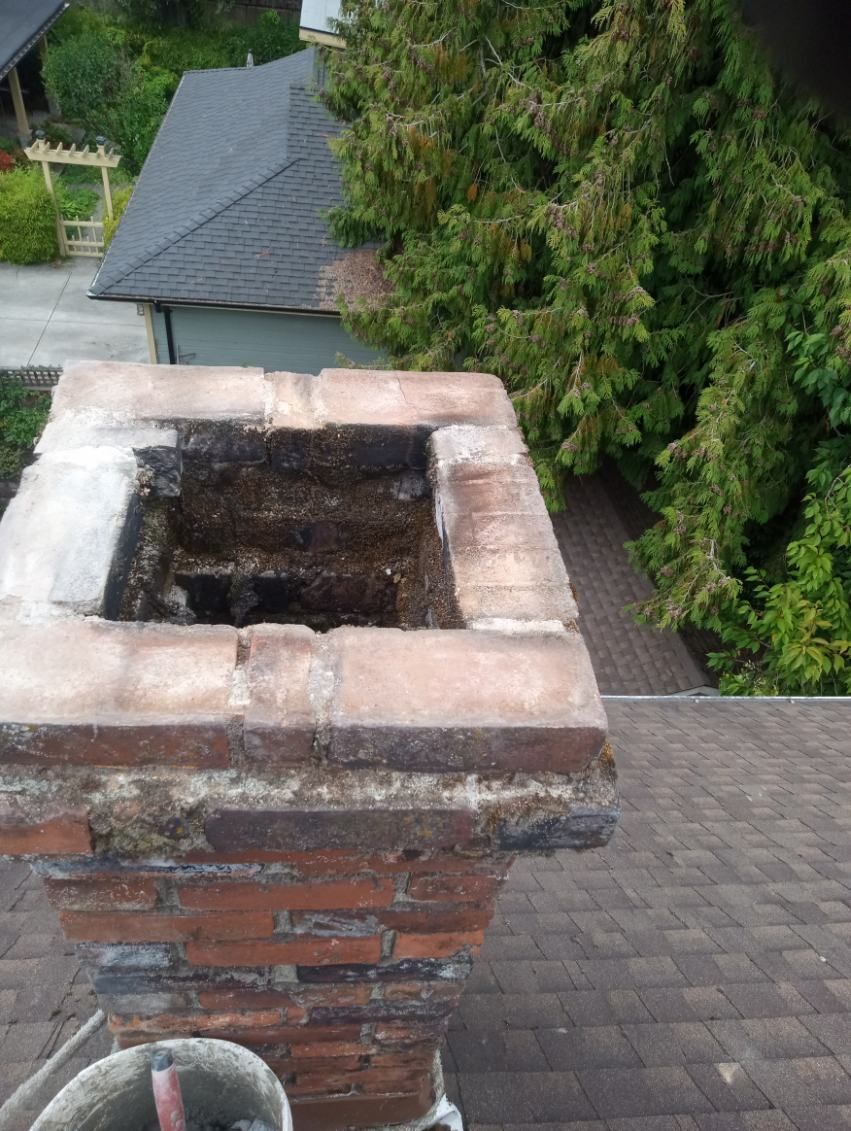 A brick chimney is sitting on top of a roof.