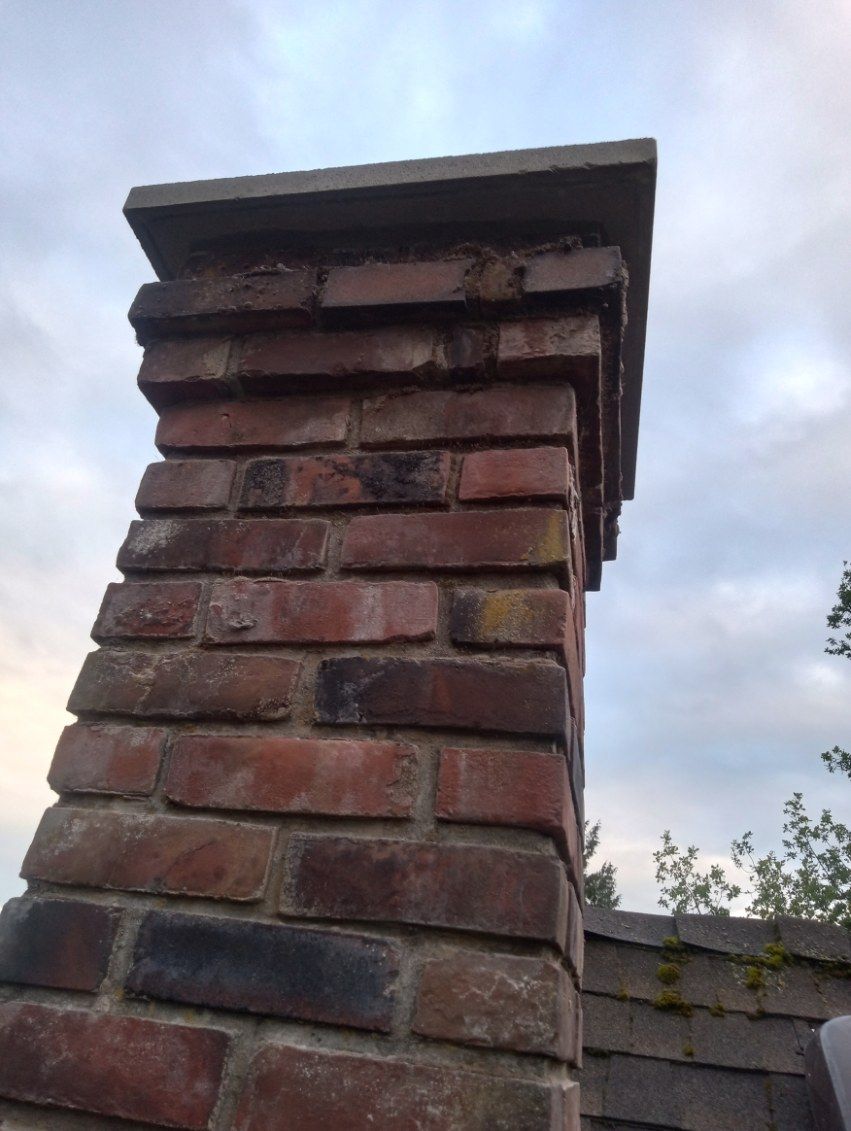 A brick chimney is sitting on top of a brick wall.