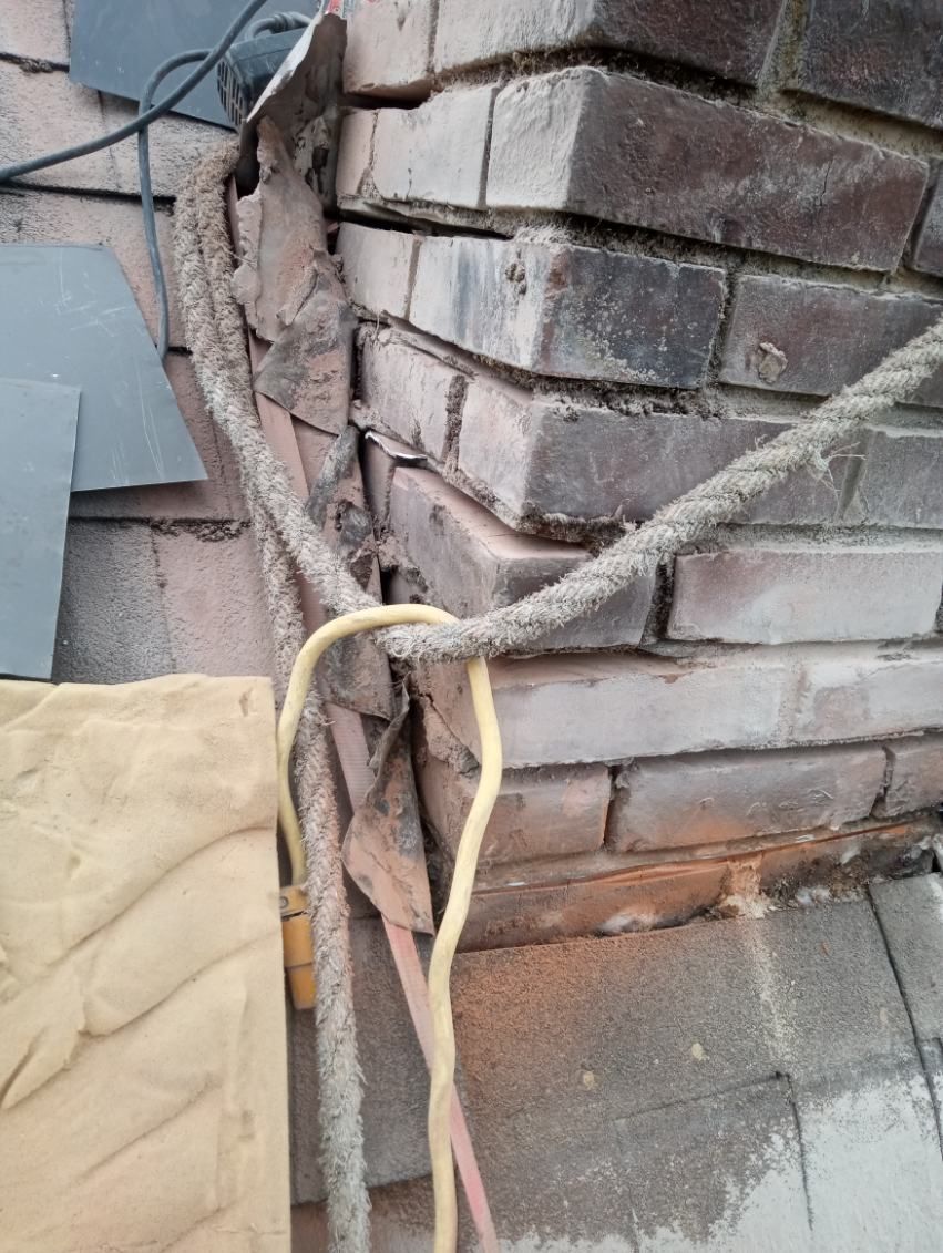 A close up of a brick wall with a rope hanging from it.