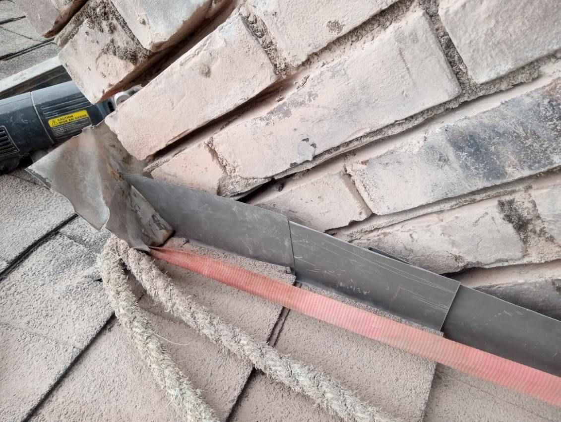 A person is cutting a piece of metal on a brick wall.