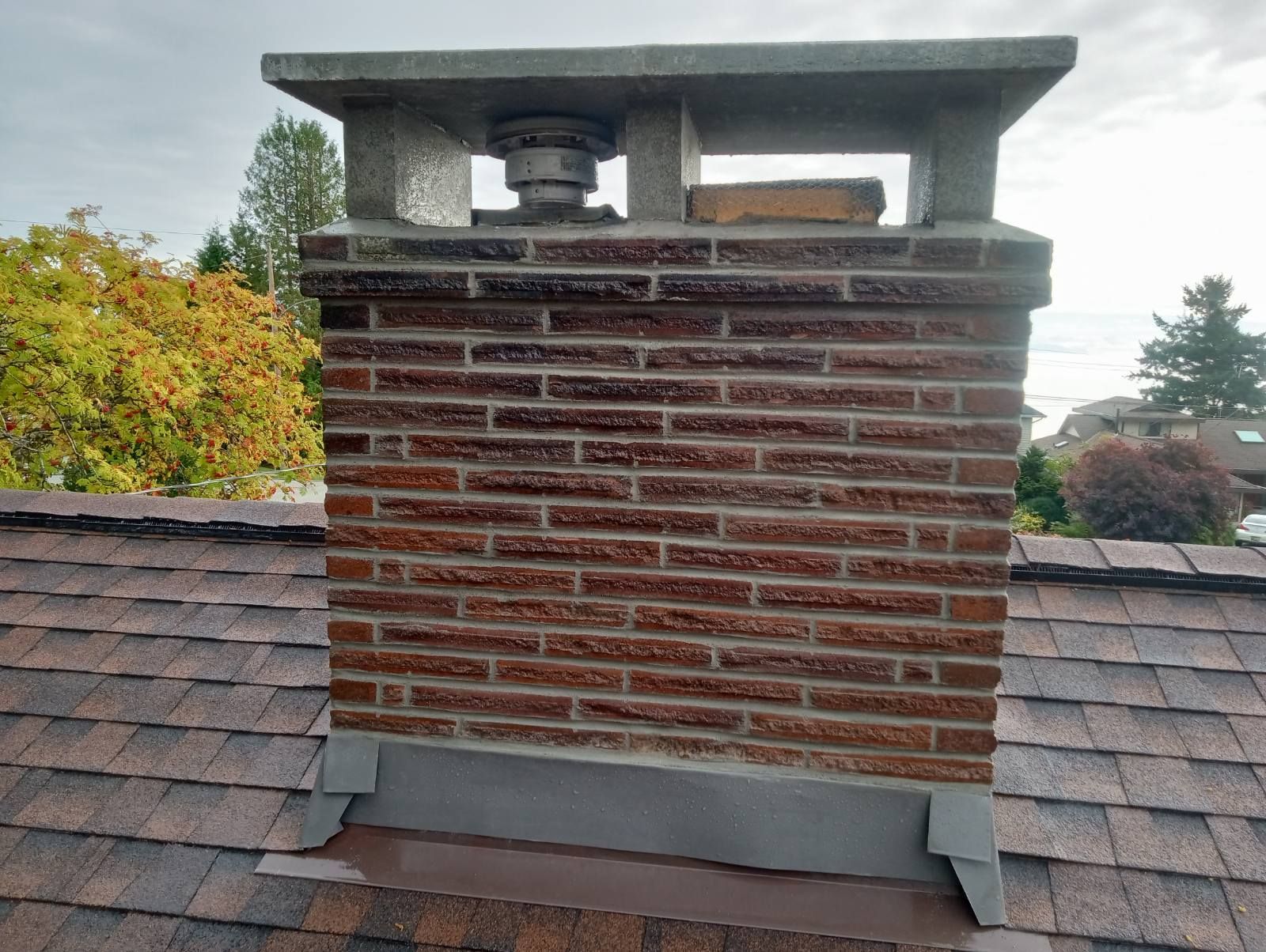 A brick chimney is sitting on top of a roof.