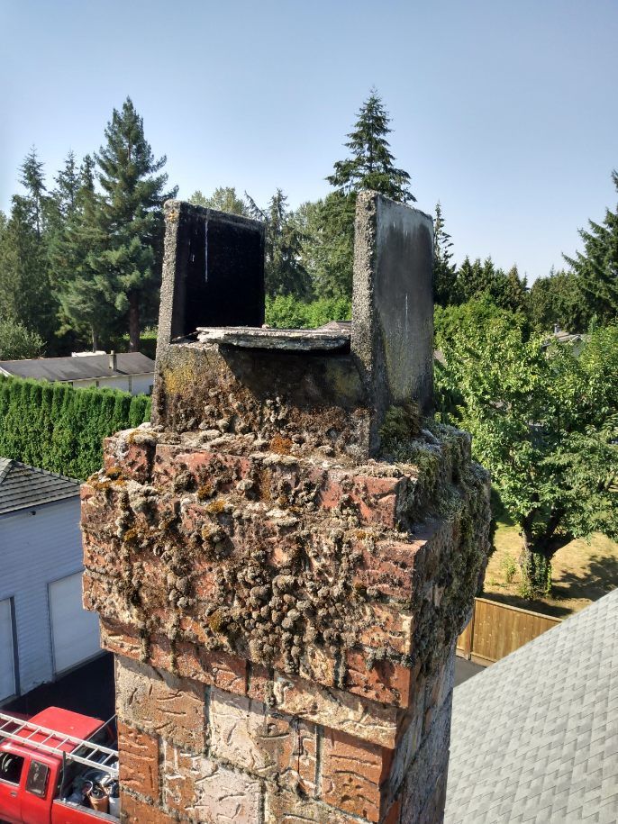 A red truck is parked in front of a brick chimney.