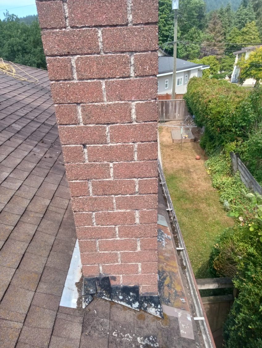 A brick chimney is sitting on top of a roof.