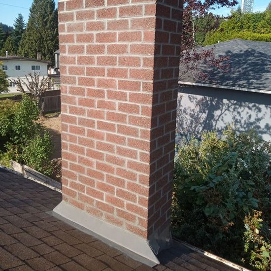 A brick chimney is sitting on top of a roof