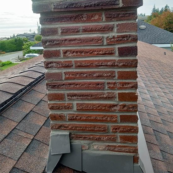 A brick chimney is sitting on top of a roof.