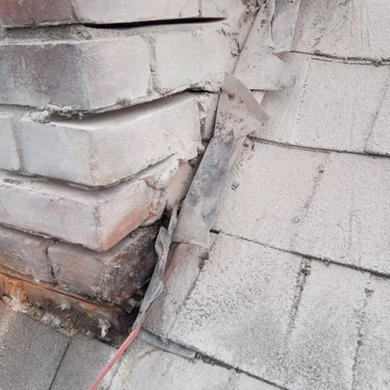 A close up of a brick wall with a roof in the background.