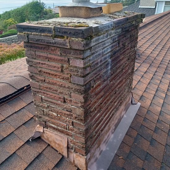 A brick chimney is sitting on top of a roof.