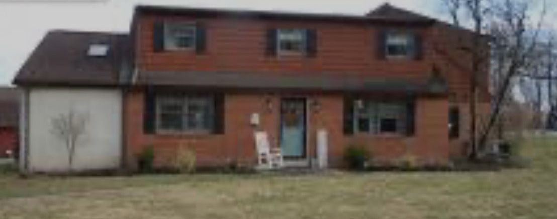 A large brick house with a lot of windows and shutters