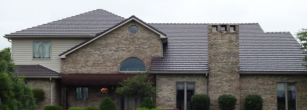 A large brick house with a gray roof and a chimney