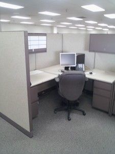A cubicle in an office with a computer on the desk.