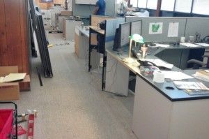 A row of cubicles in an office with a man standing in the background.